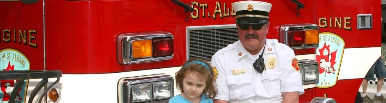 Child sitting with fireman on fire truck